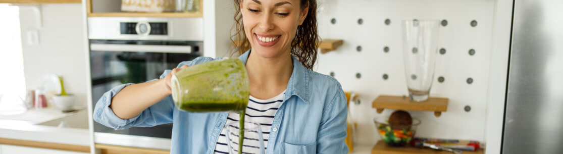 Young woman preparing a green smoothie at home