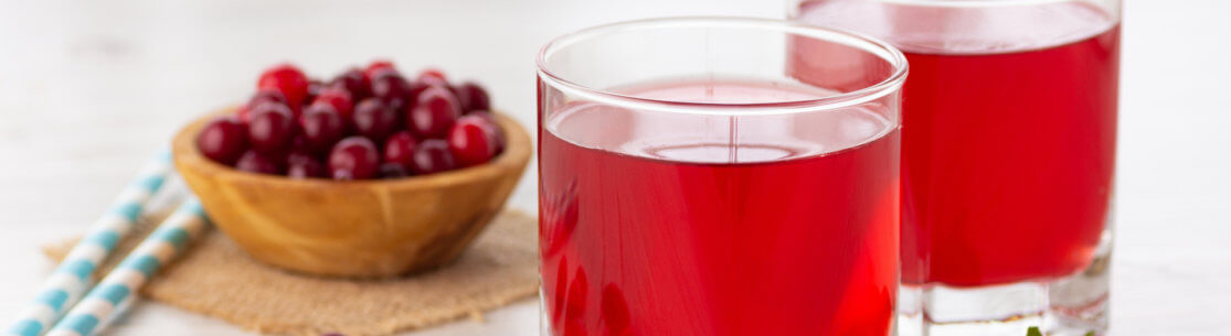 Glass with fresh organic cranberry juice and red cranberries.
