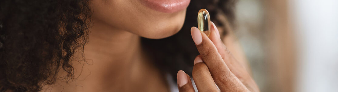 Beauty Supplement. Closeup Of Smiling Black Woman Taking Vitamin Pill Capsule, Having Diet Nutrition, Cropped Image